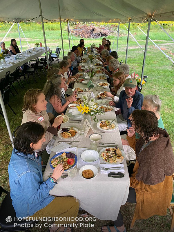 Photo shows a long table hosting 20 people at a potluck.