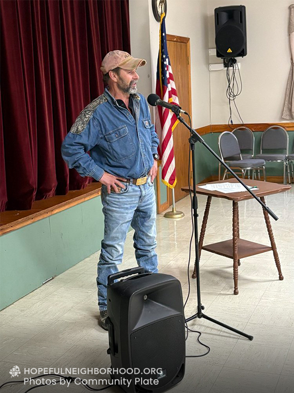 A man is talking into a microphone inside a community center.